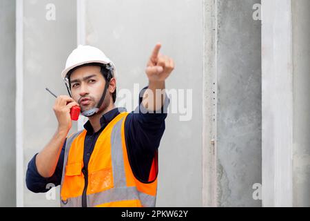 Young man engineer using radio command with worker in construction site, architect or contractor speak to radio for control and planning development s Stock Photo