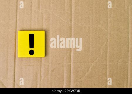 Exclamation mark drawn on wooden block over cork board background. Stock Photo