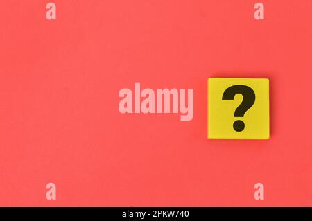 Question mark drawn on wooden block over red background. Stock Photo