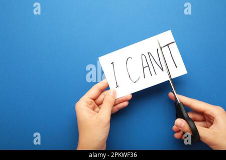 Woman hand holding card with the text i can't, cutting the word t so it written i can. Success and challenge concept. Top view Stock Photo