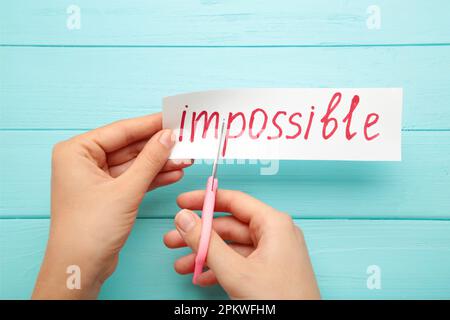 man hand holding card with the text impossible, cutting the word im so it written possible. success and challenge concept. Top view Stock Photo