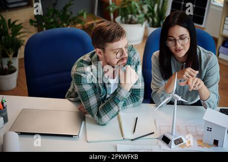 Engineers discussing plastic model of wind turbine for client Stock Photo
