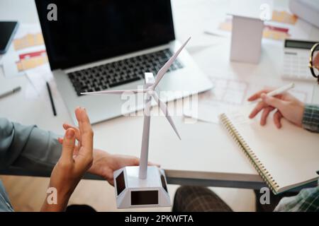 Team of sustainable energy engineers discussing model of wind turbine for new big project Stock Photo