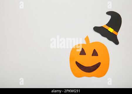Witch hat with pumpkin on grey background. Halloween paper decorations on grey background with copy space. Top view Stock Photo