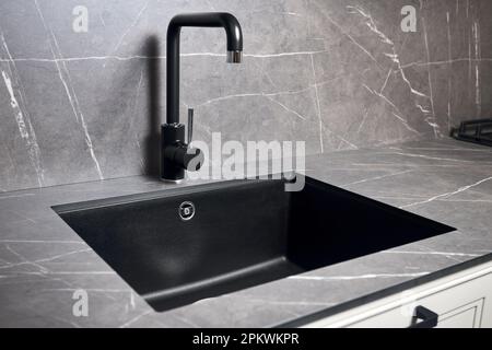 Kitchen sink area with black square matte sink tap in contemporary style. Matte black and stoneware countertop kitchen design. Stock Photo