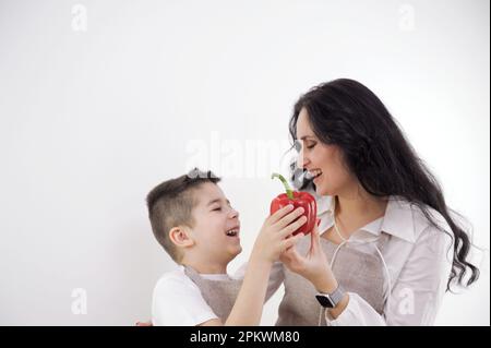 Happy woman chopping red bell pepper while standing with children in kitchen. High quality photo Stock Photo