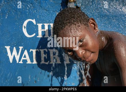 A young girl cool of under one of one of Chembe's village ( at Cape Maclear ) water taps supplied by the malawi government. Stock Photo