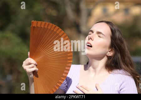 Woman in summer suffering heat stroke and fanning in a park Stock Photo