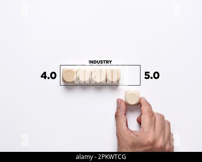 Technological change in business industry. Moving from industry 4.0 to 5.0. Hand places a wooden cube to the loading bar moving from industry 4.0 to 5 Stock Photo