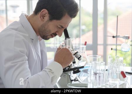 Young scientist medical worker in lab , doing a microscope analysis in a laboratory doing research Stock Photo