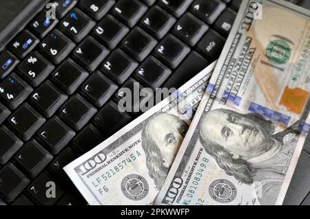 Close-up US dollars on an old laptop with a worn out keyboard. Stock Photo
