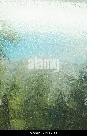Raindrops on glass during rain, large drops. Landscape with raindrops falling on the window of the house. Blurred horizon view. macro photo Stock Photo