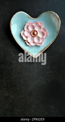 Coconut milk flavor, pastel pink color, Sam Pan Nee traditional Thai handcraft snack on pastel blue heart shape plate, Dark background, vertical image Stock Photo