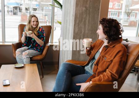 Two young women laughing together in coffee shop Stock Photo