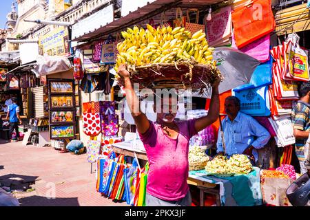 Mysore, India - 12.01.2023 : Devaraja Market, Mysore old traditional street market, man carrying bananas in a basket on his head. High quality photo Stock Photo