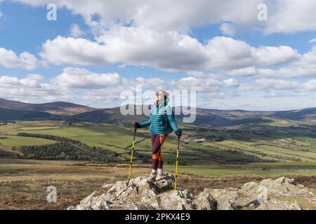 female hiker standing on top of mountain looking towards the sun Stock Photo