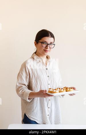 Young female confectioner holding a tray with homemade lemon cakes Stock Photo