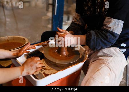 potter with student on potter's wheel makes dishes from clay Stock Photo