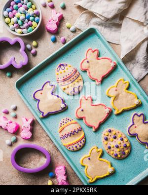 easter cookies shaped like eggs and bunnies on green tray from above. Stock Photo