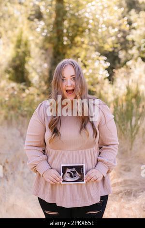 Shocked pregnant mother holding ultrasound of twins Stock Photo