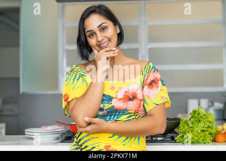 Beautiful hispanic mother or housewife at kitchen indoors at home Stock Photo