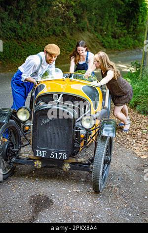 men and woman push broken down classic car on road in the countryside.couple pushing their broken-down car . Stock Photo