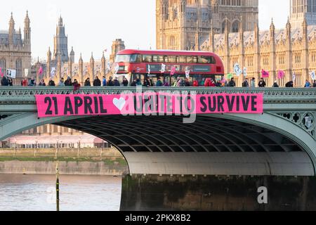 Extinction Rebellion activists perform a banner drop on Westminster Bridge declaring 'Unite To Survive', advertising future climate protests. Stock Photo