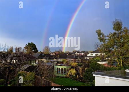 A double rainbow forming over the rooftops of a suburban landscape, Shepperton Surrey England UK Stock Photo