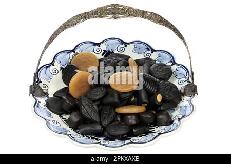 Dutch licorice candies on a Delftware plate isolated on white background Stock Photo