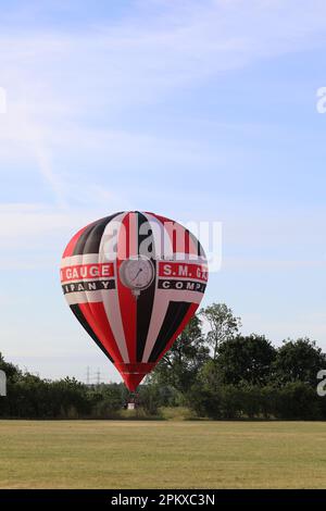 A red, black and white hot air balloon has landed in an east London park after flying over the city of London as part of the 2019 Lord Mayor's Balloon Stock Photo