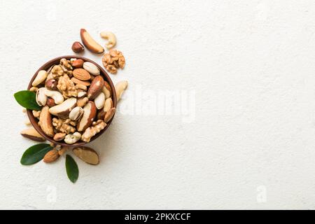 mixed nuts in bowl. Mix of various nuts on colored background. pistachios, cashews, walnuts, hazelnuts, peanuts and brazil nuts. Stock Photo