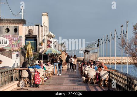 terrace full of tourists eating, sitting on the chairs and the table in the restaurant bar Mala Vita in Marina de Dénia, Alicante, Spain, Europe Stock Photo