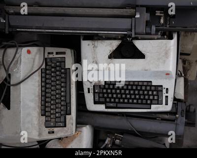 Picture of typewriters with QWERTY keywords being thrown away due to obsolescence, dirty and broken. Stock Photo
