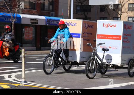 A ByNext dry cleaning and laundry delivery bike messenger on a pedal assist electric cargo trike, cargo bicycle in New York City. Stock Photo