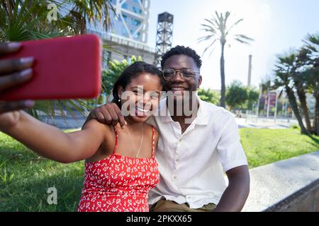 Happy young African American couple taking selfie with phone outdoors. Stock Photo