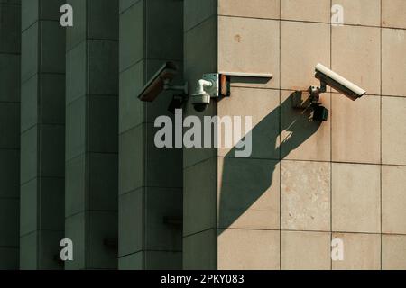 Old worn surveillance security cameras mounted on building wall, selective focus Stock Photo