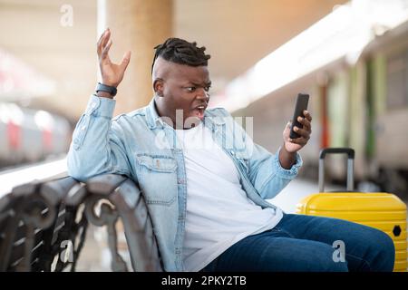 Stressed Black Guy Reading Bad Message On Smartphone At Railway Station Stock Photo