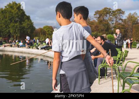 Two Brothers Exploring by the Pond in a Parisian Park Stock Photo