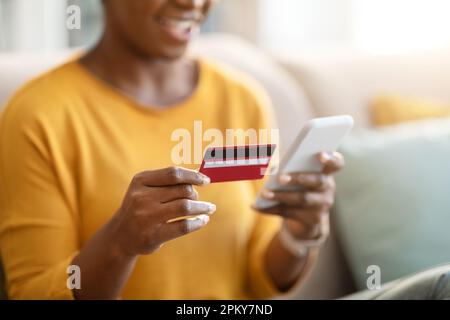 Cropped of black woman holding bank card and smartphone Stock Photo
