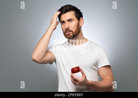 Pampering, grooming and hair style concept. Portrait of handsome middle aged man fixing his hair with lotion Stock Photo