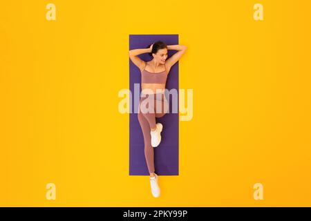 Above View Of Fitness Woman Exercising Lying Over Yellow Background Stock Photo