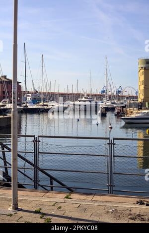 Pier  with docked boats seen from a pavement on a sunny day Stock Photo