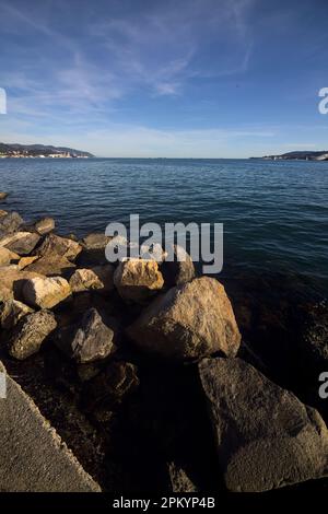 Sea  and the opposite shore of a lagoon in the distance framed by rocks at sunset Stock Photo