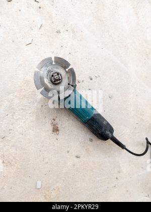The grinder machine with the diamond grinding disc for cutting the cement block on the concrete floor, front view with the copy space. Stock Photo