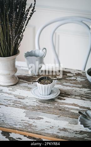 White ceramic cup of aromatic tea with fresh lavender flowers placed on wooden table Stock Photo