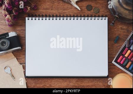 Top view of blank notepad placed near vintage camera and assorted stationery on wooden table Stock Photo