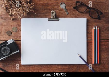 Top view of blank notepad placed near vintage camera and assorted stationery on wooden table Stock Photo