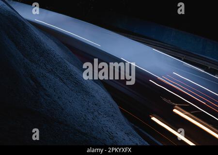 From above long exposure of asphalt roadway with driving modern cars with glowing headlights at night time in city district Stock Photo