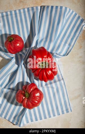 From above of ripe fresh red tomatoes placed on rough checkered tablecloth on plane table surface indoors Stock Photo