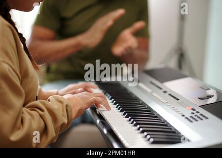 Proud teacher clapping to student playing melody on electronic piano Stock Photo